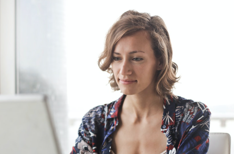 Young woman is working on laptop at her desk.