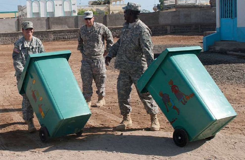 Us Army are taking the trash from trash bin on field.