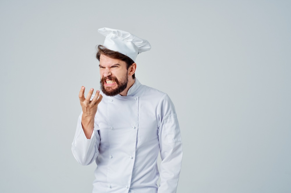 Angry chef with   hand in front of the face yelling at the camera