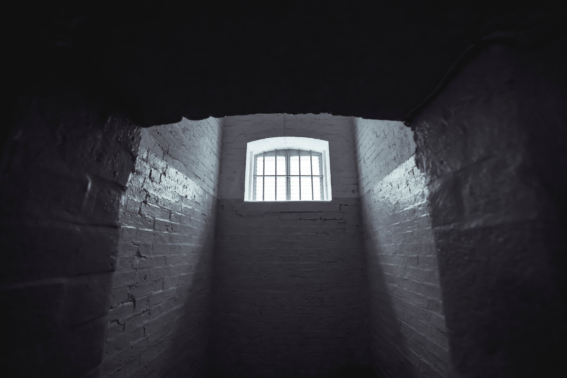 grayscale photo of prison cell hallway with window