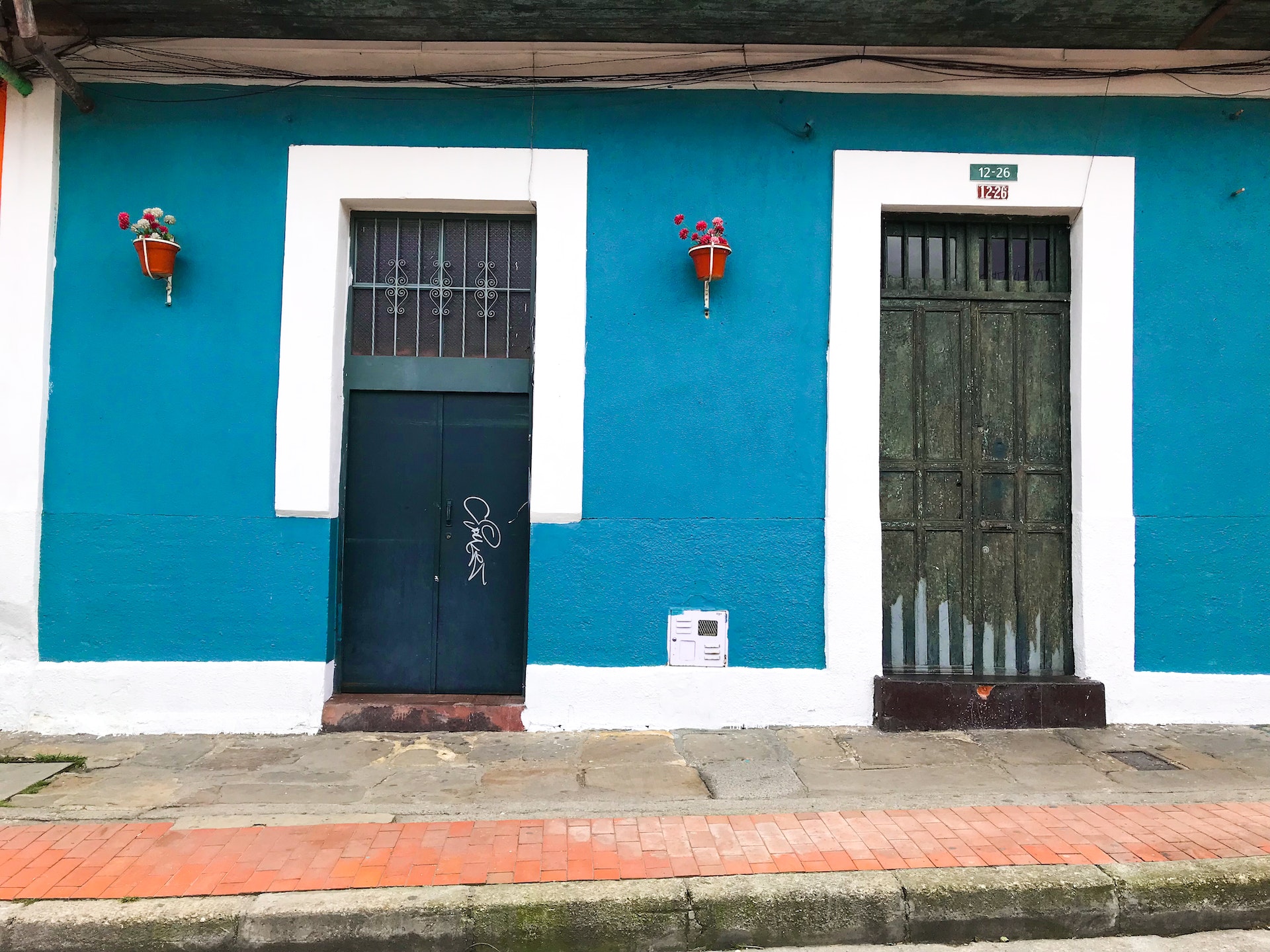 two neighboring metal doors on a light blue wall