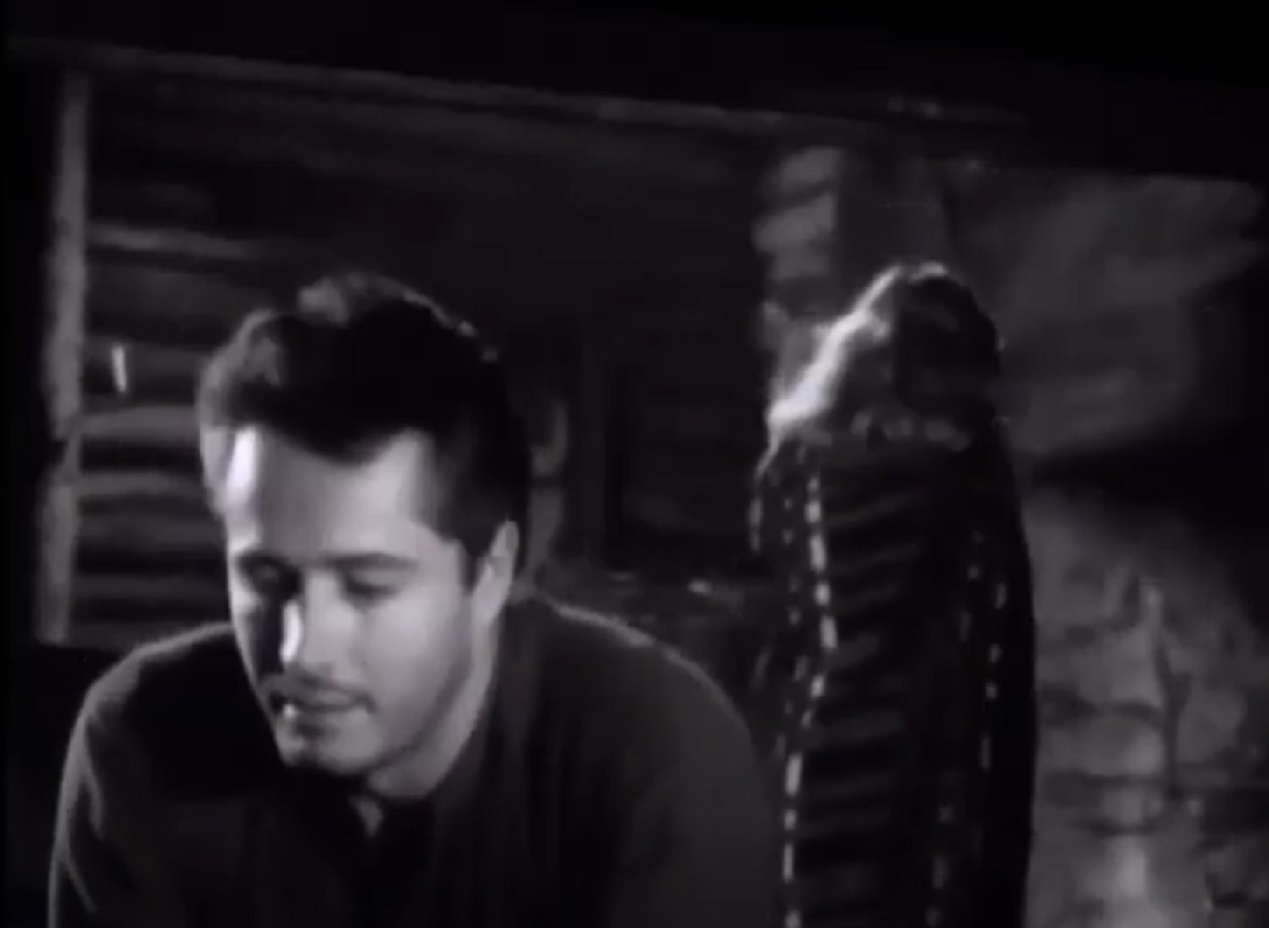 Screenshot - John Derek seating in the room and looking down - from High Hell (1958)