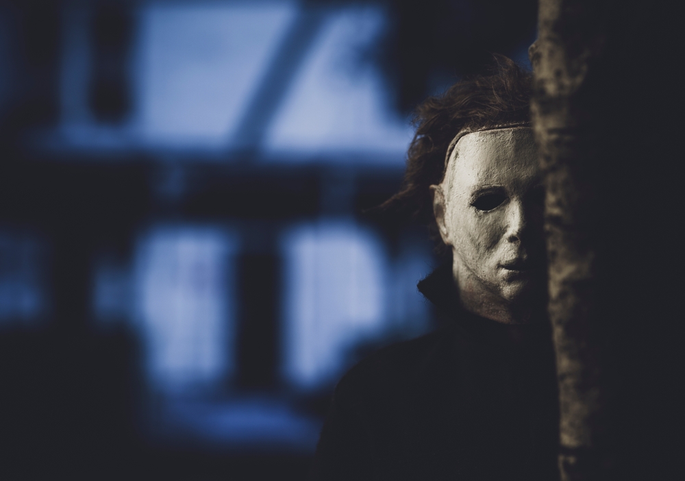 Halloween movie slasher Michael Myers lurking from behind a tree