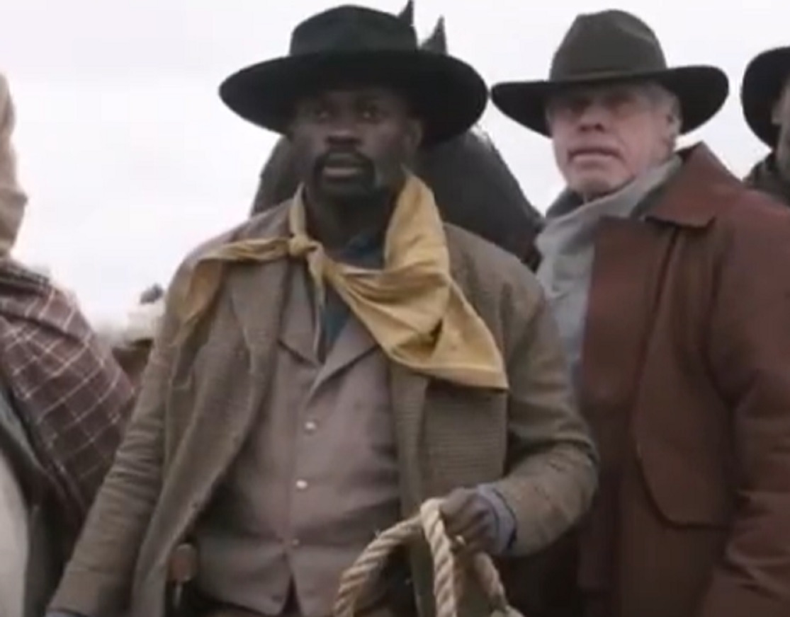 Screenshot:Bass Reeves wearing brown jacket and hat standing outside - from H.e.l.l on the Border (2019)