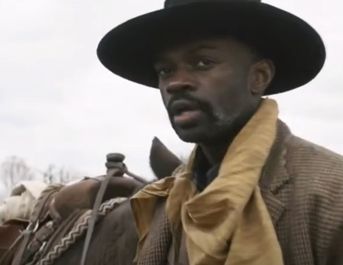 Screenshot:Bass Reeves wearing brown jacket and hat standing outside - from H.e.l.l on the Border (2019)