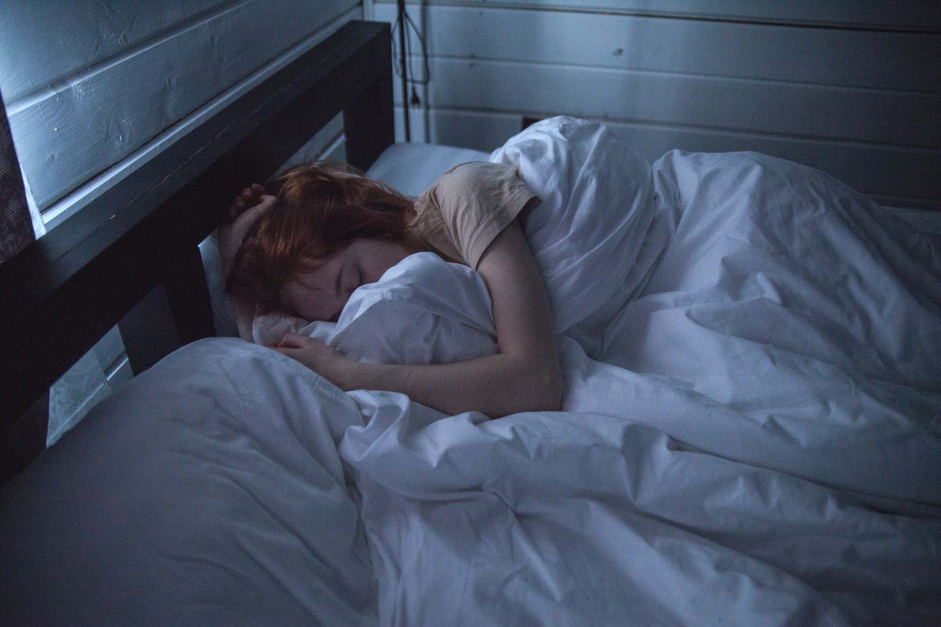 woman sleeping in her wooden bed with white sheets