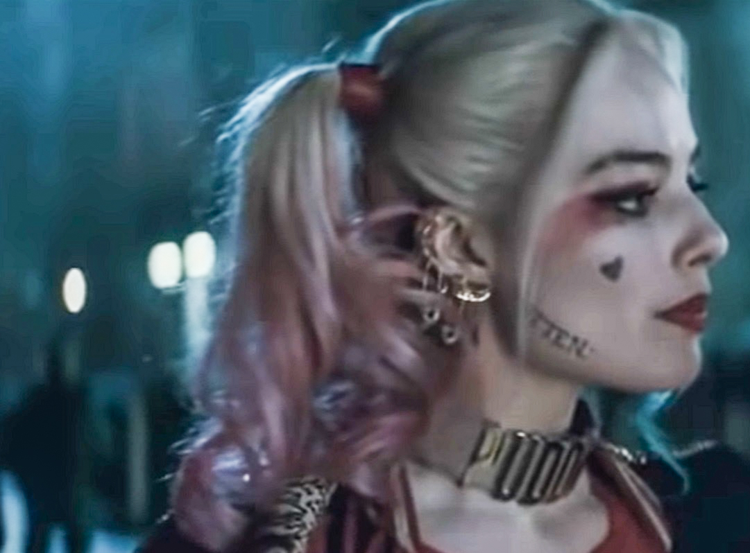 Screenshot: Harley Quinn (Margot Robbie) wearing red shirt is looking at side - from Suicide Squad (2016)