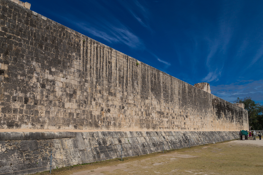 Mesoamerican ballgame on a brick wall visited by tourists