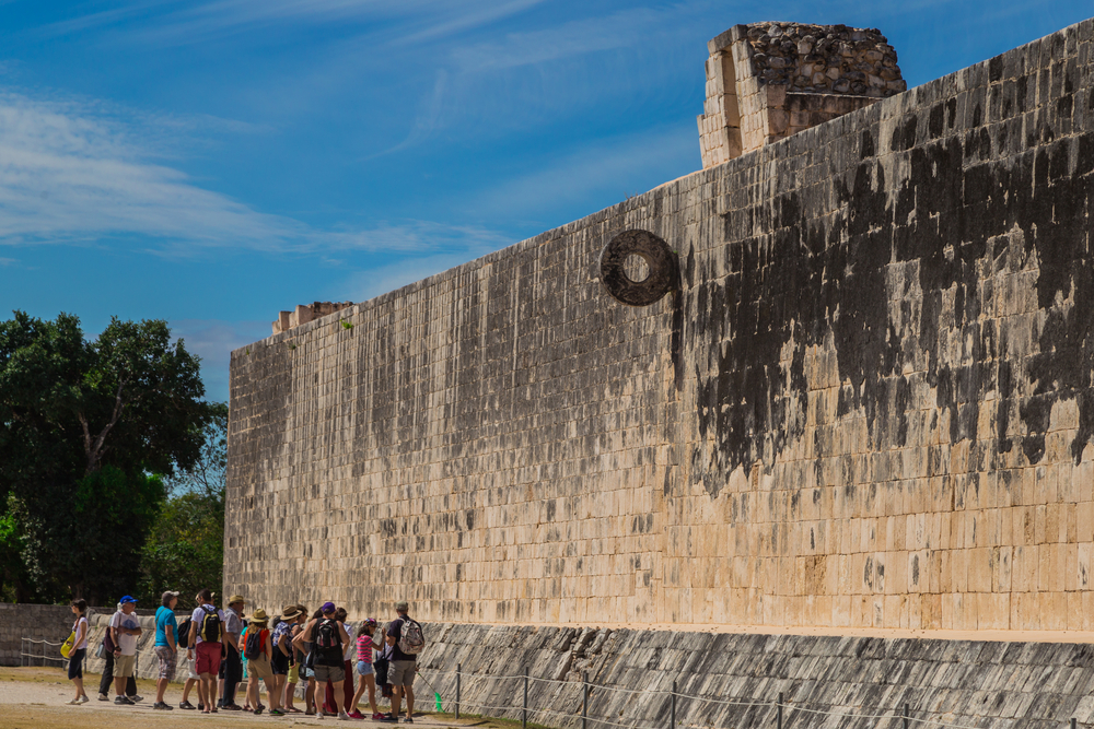 Mesoamerican ballgame on a brick wall visited by tourist