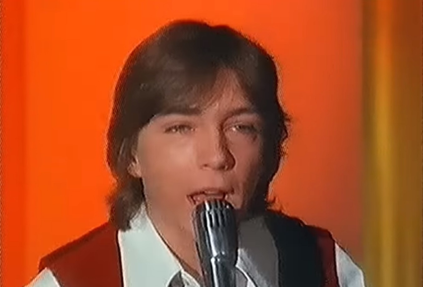 Screenshot: David Cassidy is performing live on orange background - from David Cassidy: The Last Session (2018)
