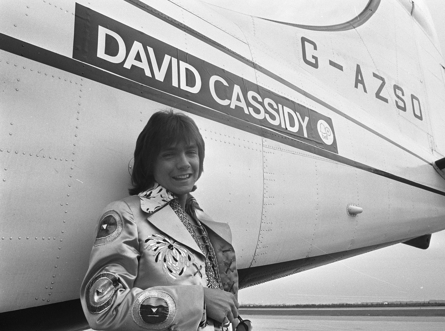 David Cassidy is standing outside next to a plane with his name on it - 1972
