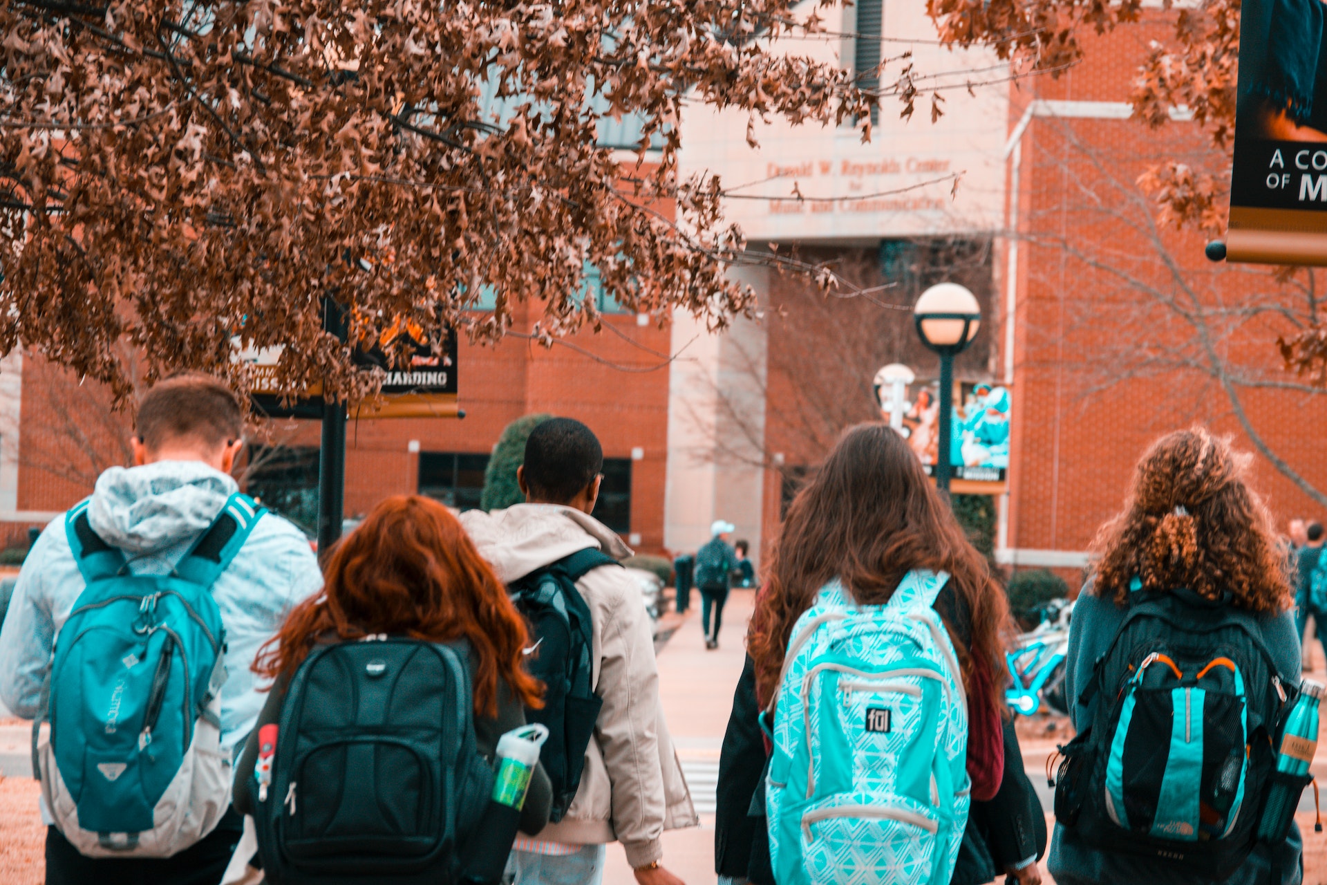 student wearing backpacks and walking in a college campus