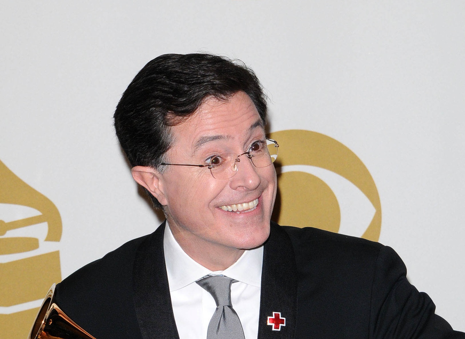 Stephen Colbert wearing black suit is looking at side and smiling - 2010