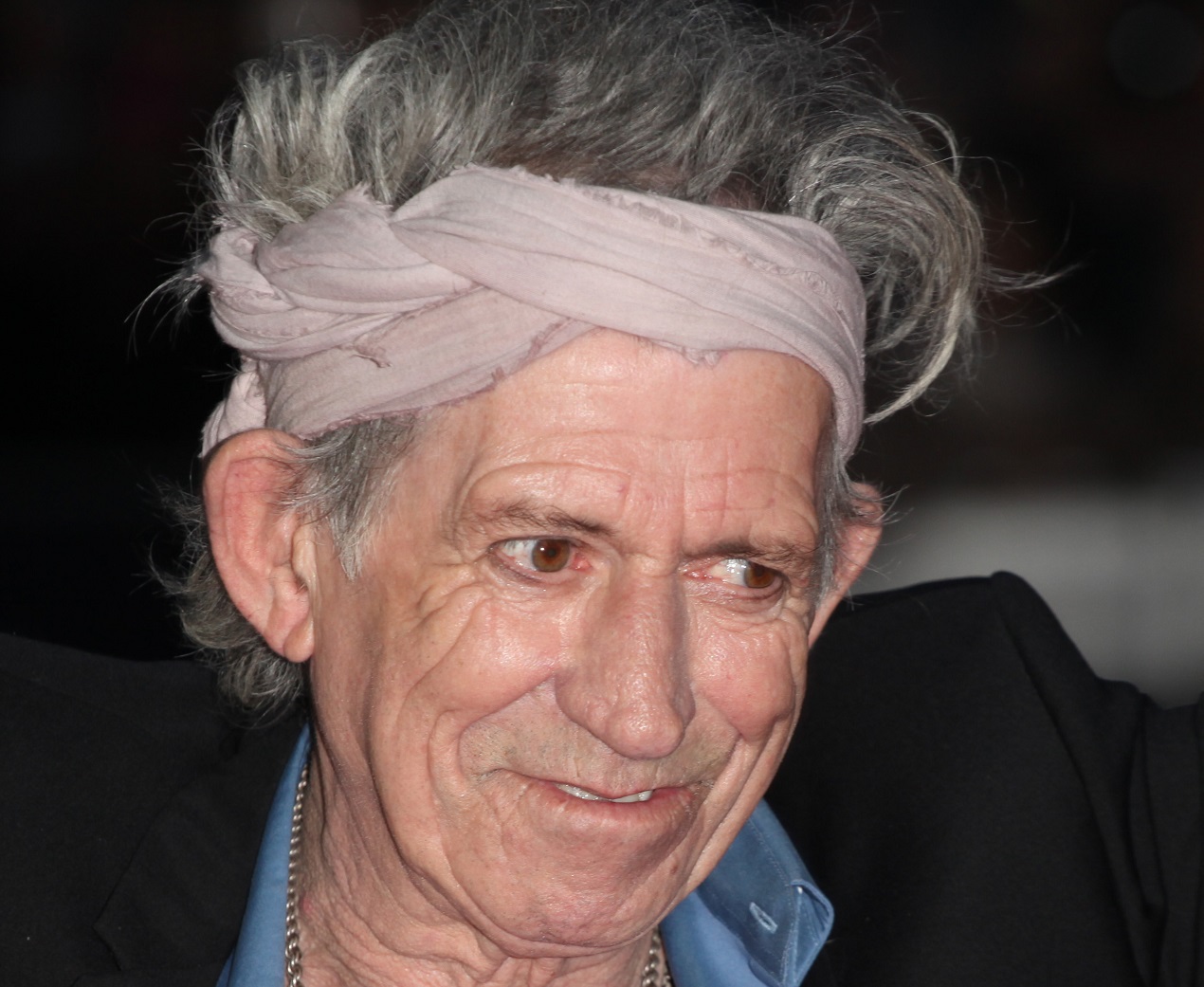 Keith Richards wearing grey bandana and black suit is looking at side - 2012