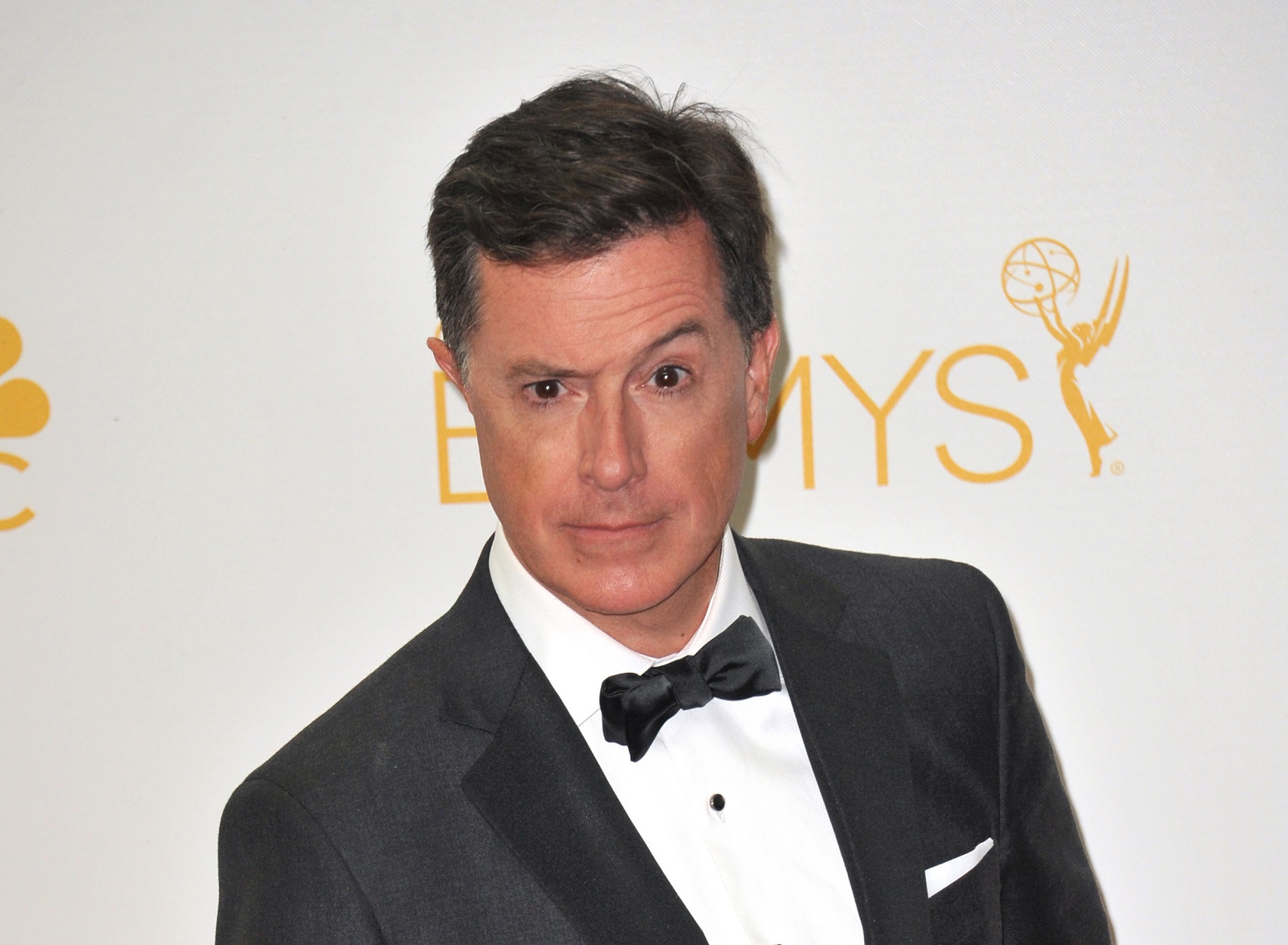 Stephen Colbert wearing black suit is making face at camera - 2014