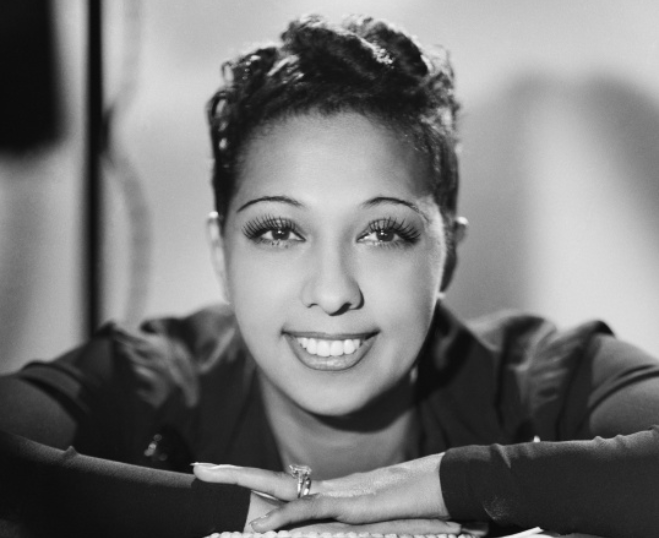 Grayscale portrait photo of Josephine Baker wearing a black dress smiling