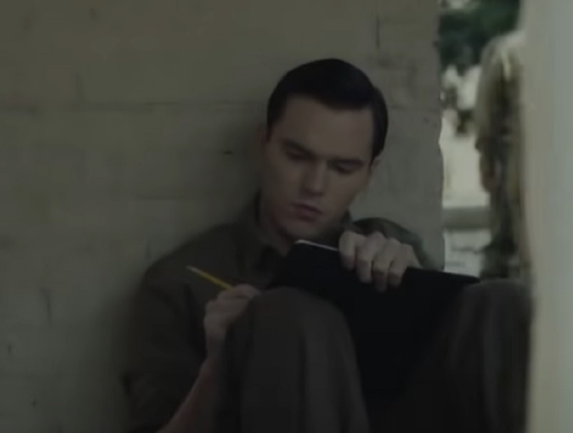 Screenshot: J.D. Salinger wearing dark suit is seating on the floor and writing - from Rebel in the Rye (2017)