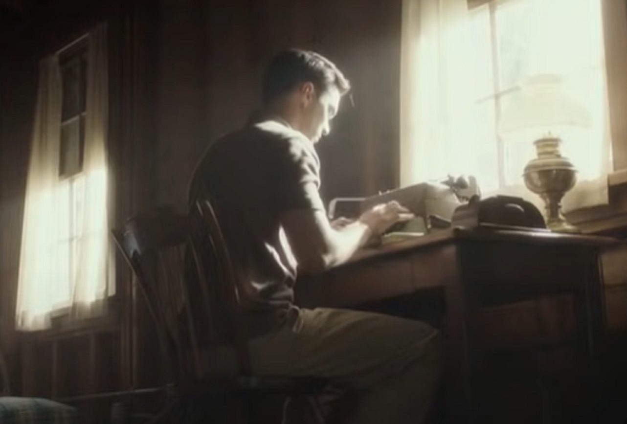 Screenshot: J.D. Salinger wearing dark suit is writing on desk - from Rebel in the Rye (2017)