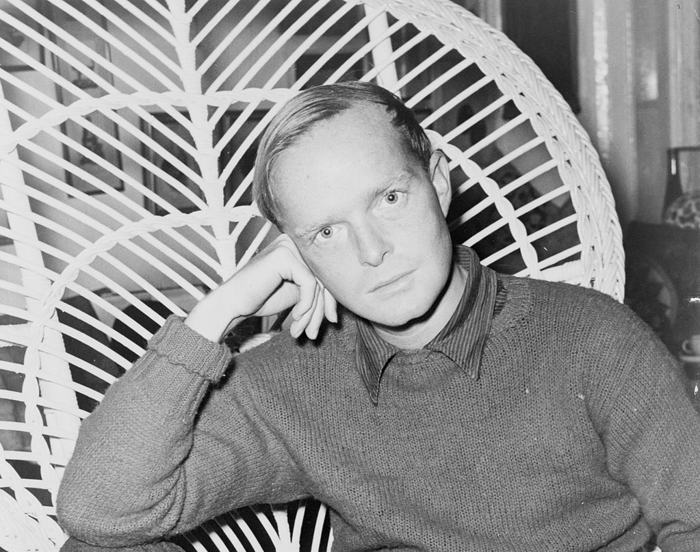Truman Capote, half-length portrait, facing front, seated in a chair, resting head on his hand