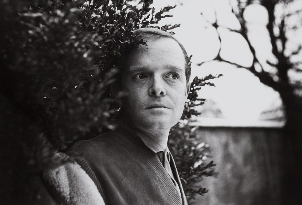 Grayscale Portrait Photo Of the writer Truman Capote standing in the garden facing the camera
