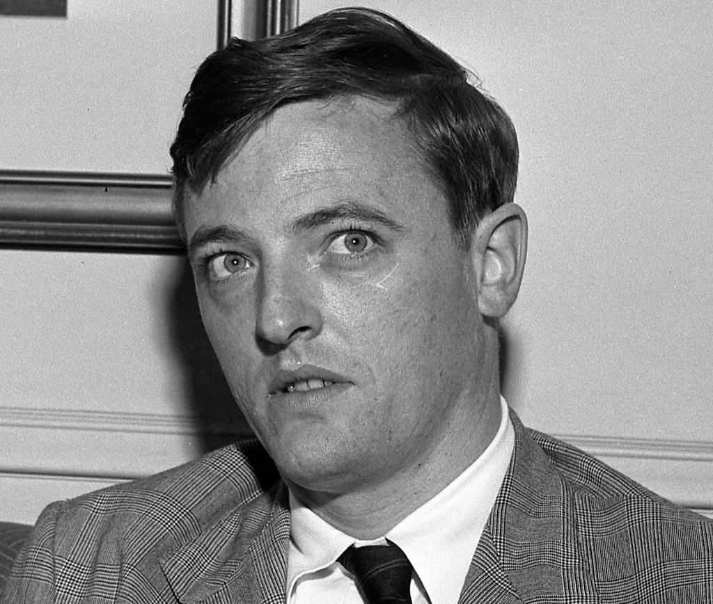 Grayscale Portrait Photo of William F. Buckley Jr. wearing a fray suit white shirt and a black tie