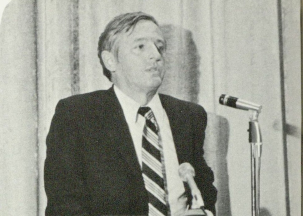 William F. Buckley, Jr. speaking at the University of San Diego wearing a black suit white shirt and a tie