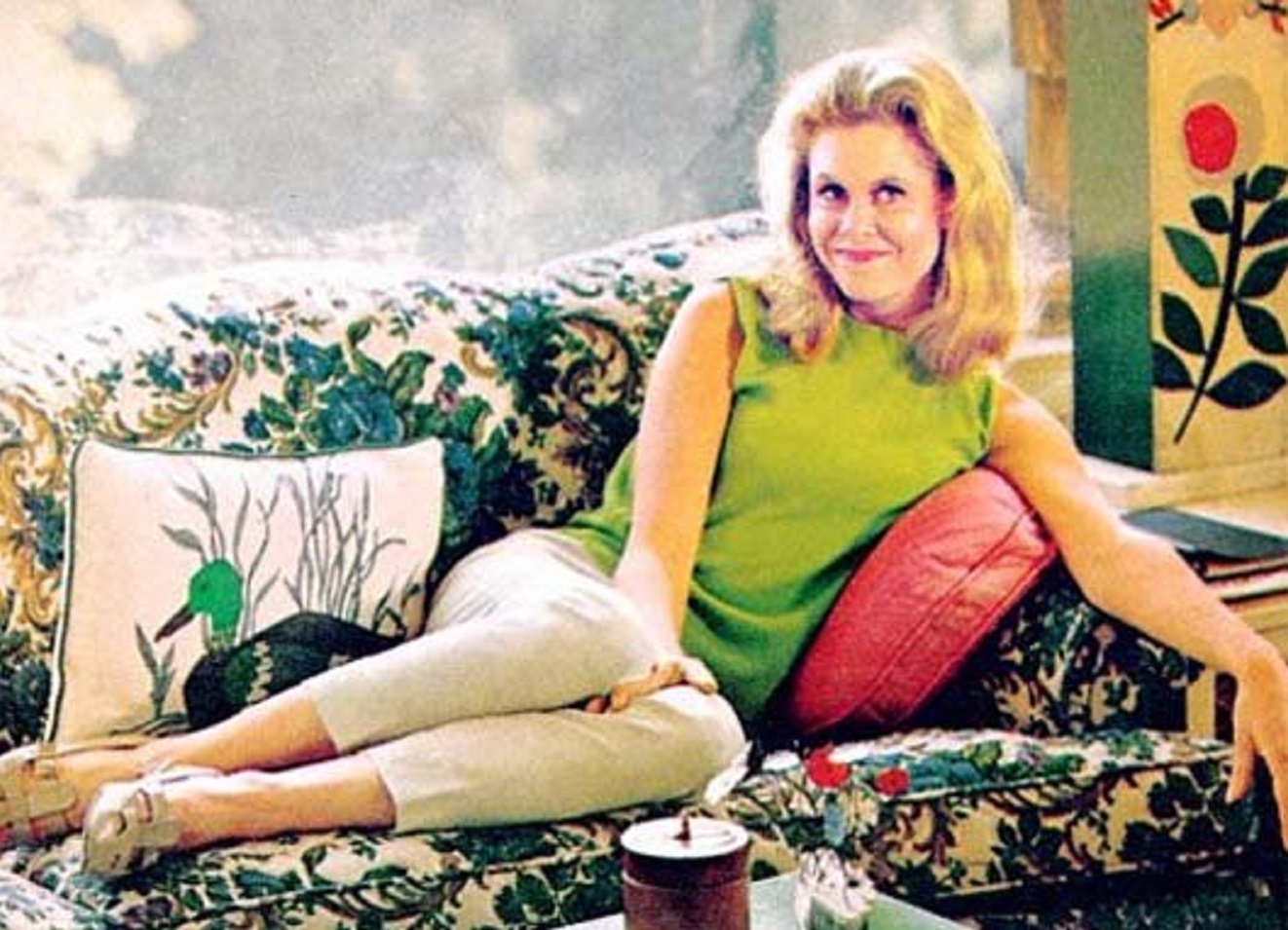 Photo of Elizabeth Montgomery seating on the bed and looking at camera.