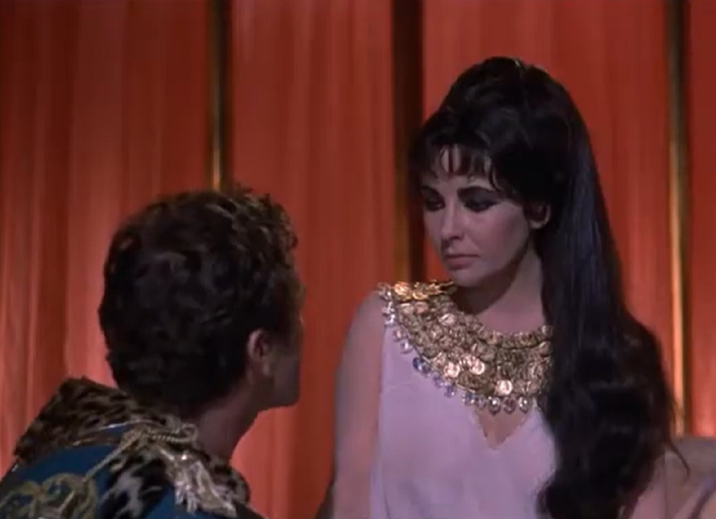 Screenshot: (Elizabeth Taylor) Cleopatra wearing white dress is looking at other person - from Cleopatra (1963)