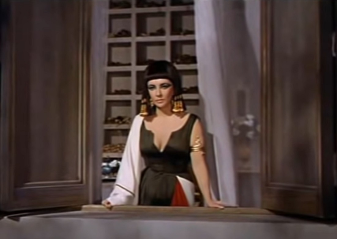 Screenshot: (Elizabeth Taylor) Cleopatra wearing black dress is looking from balcony  - from Cleopatra (1963)