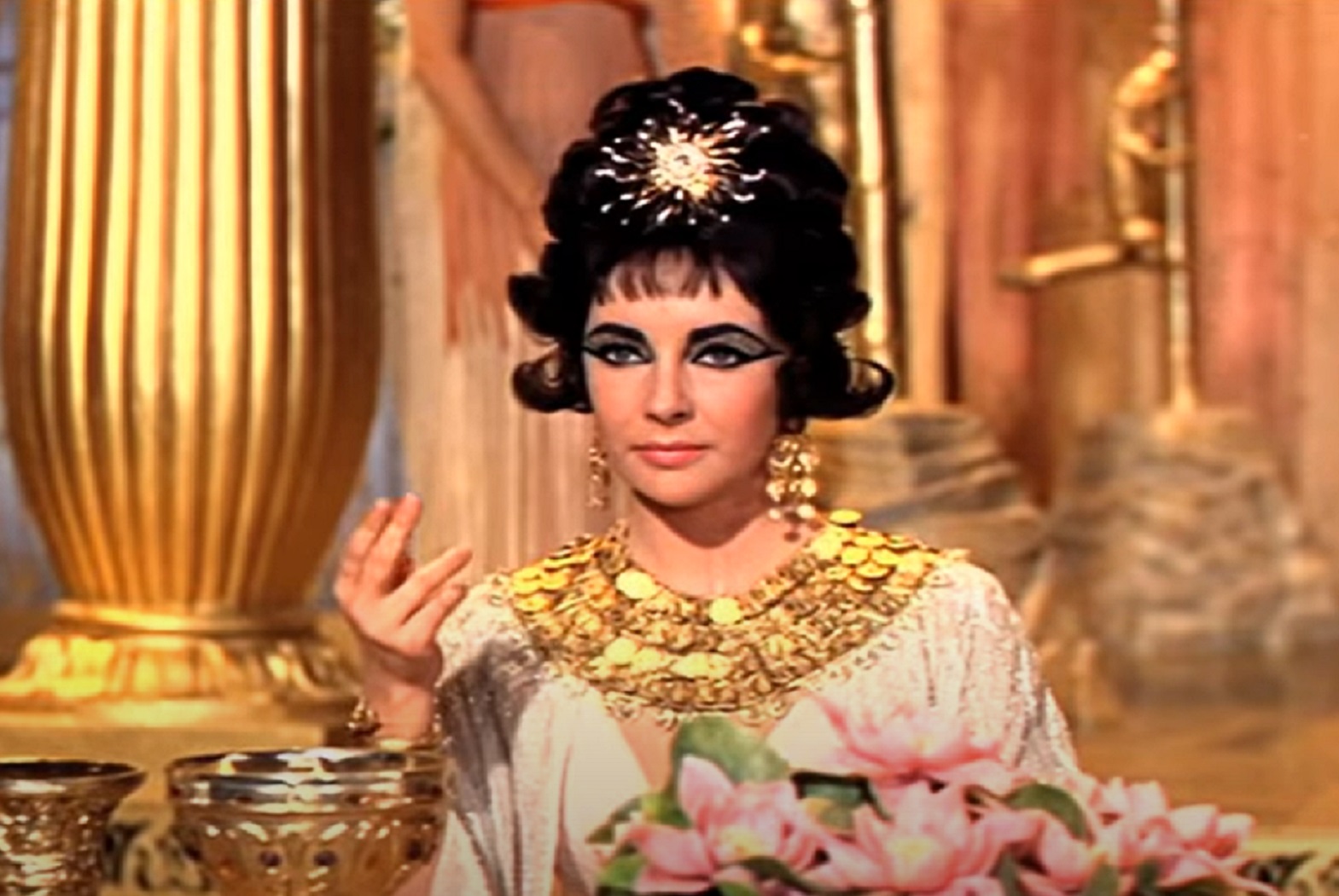 Screenshot: (Elizabeth Taylor) Cleopatra wearing white dress with golden necklace  - from Cleopatra (1963)