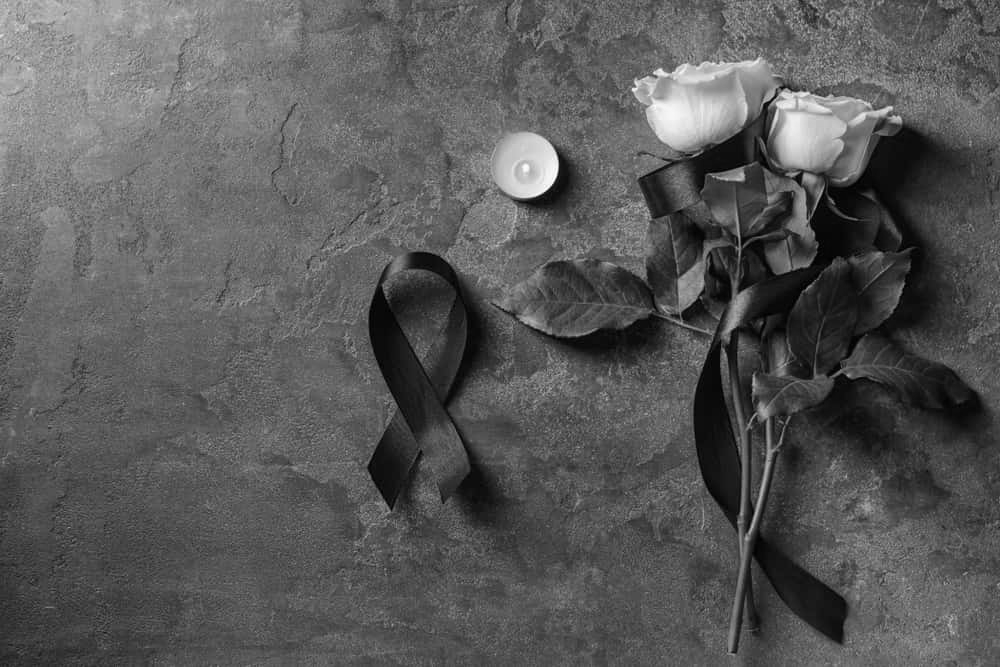 Black mourning ribbon, flowers and candle