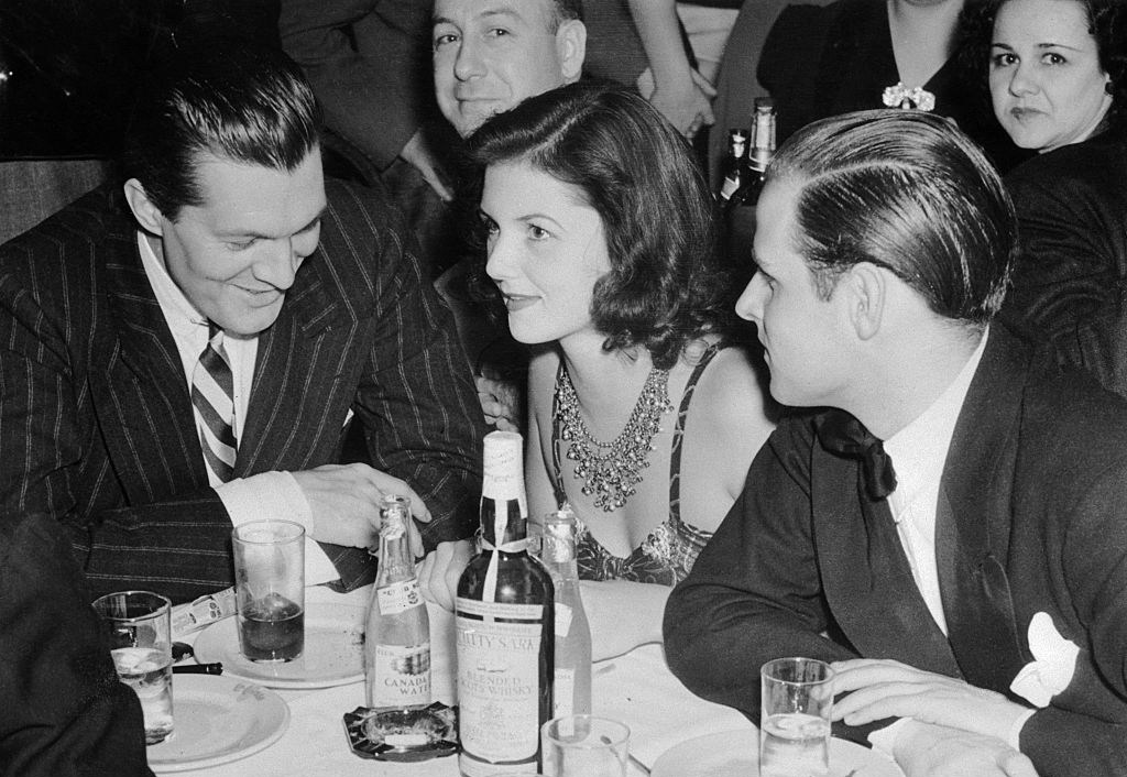 Grayscale Photo of Brenda Frazier With Peter Arno and Billy Livingston sitting on a restaurant table