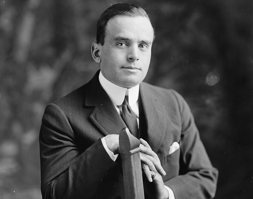 Grayscale Portrait Photo of the Actor Douglas Fairbanks sitting on a chair wearing a dark suit