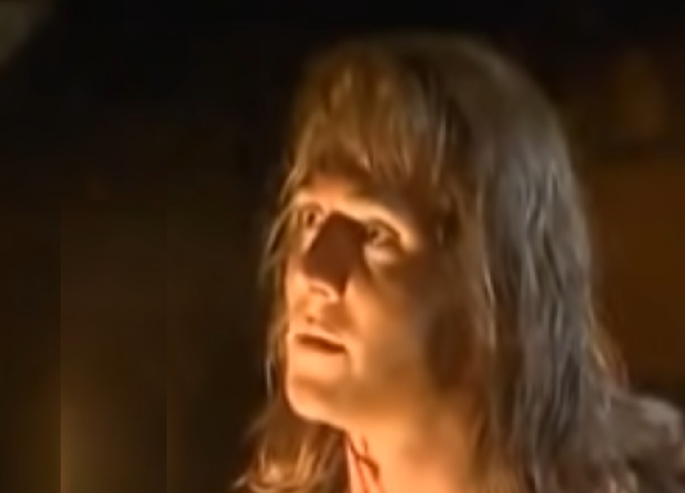 Screenshot: (Mark Umbers) Perkin Warbeck with long hair is looking at side - from Princes in the Tower (2005).