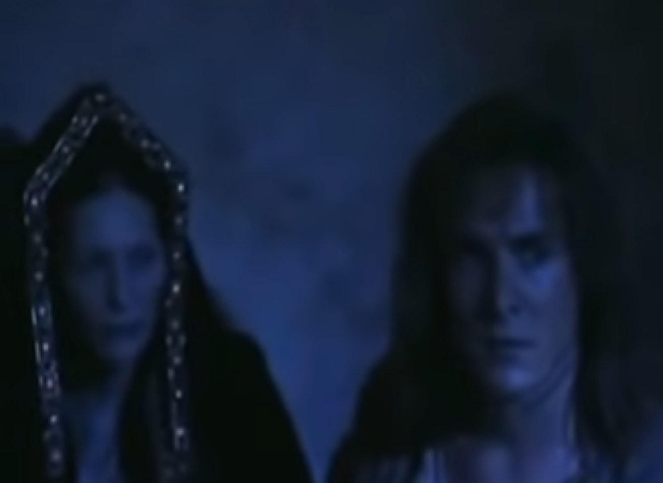 Screenshot: (Mark Umbers) Perkin Warbeck with long hair is hiding in darkness in company of female - from Princes in the Tower (2005).