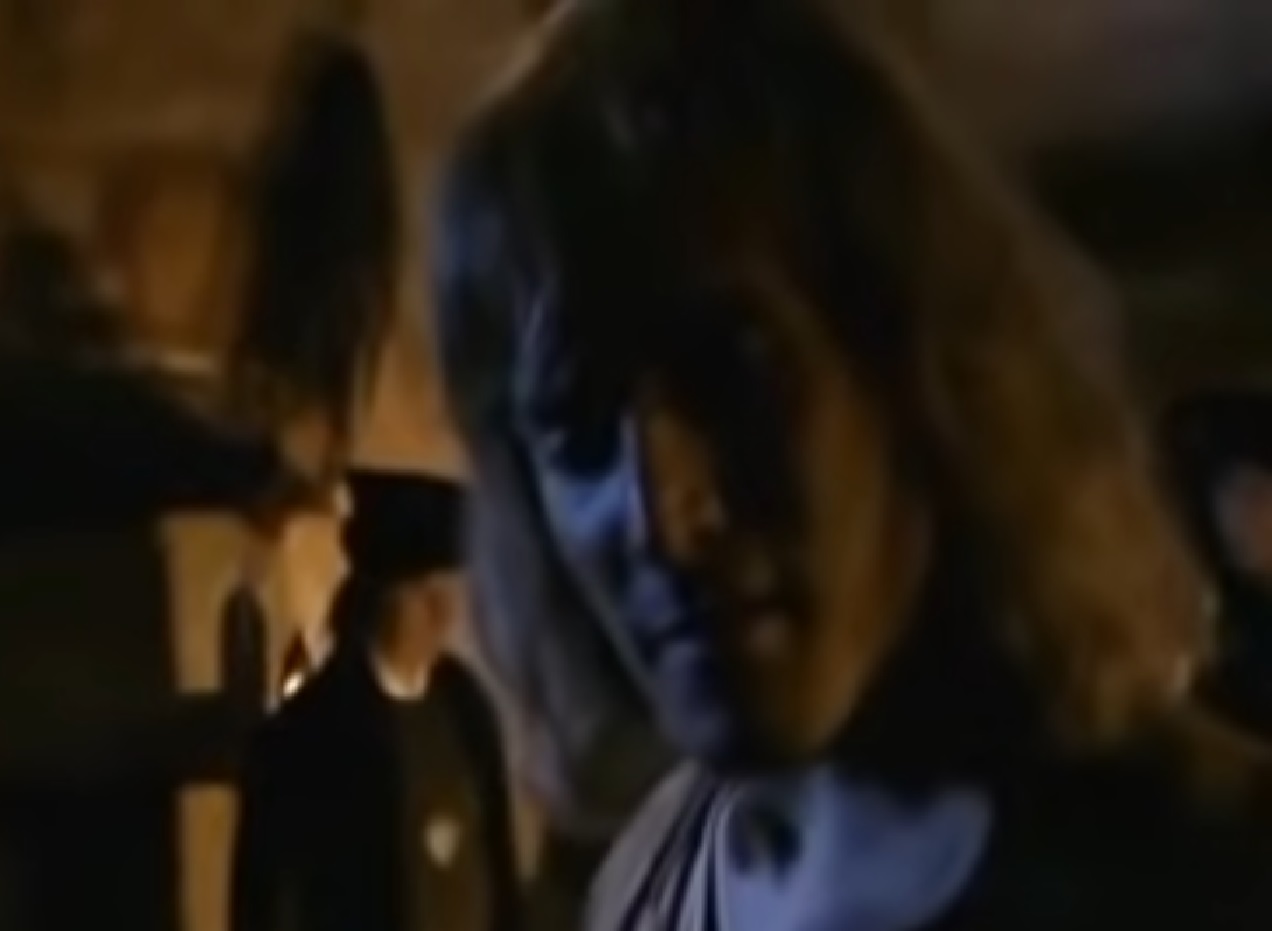 Screenshot: (Mark Umbers) Perkin Warbeck with long hair is talking with other person in prison - from Princes in the Tower (2005).