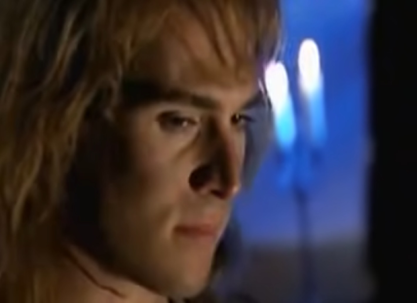 Screenshot: (Mark Umbers) Perkin Warbeck with long hair is looking at side - from Princes in the Tower (2005).