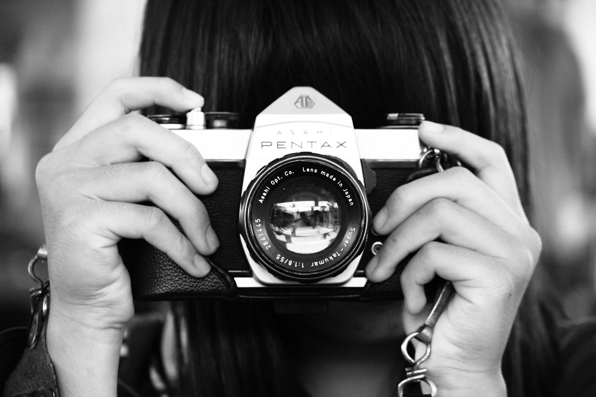 grayscale photography of a woman holding vintage camera