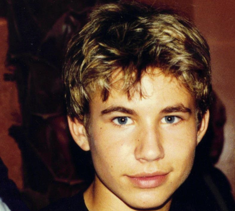 Portrait Photo of the Teen Idol Jonathan Taylor Thomas wearing a black shirt, smiling