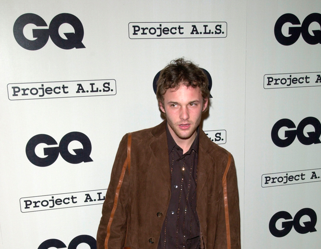 Actor BRAD RENFRO at the second annual GQ Magazine Hollywood Issue party, wearing a long brown coat, black shirt, facing the camera