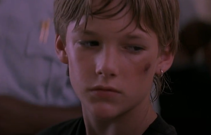 Screenshot of the actor Brad Renfro from the Movie The Client (1994) depicting a boy with a bruised face wearing a earring