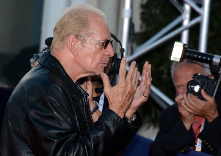Profile Picture of the Director Larry Clark wearing a black leather jacket with his hands raised