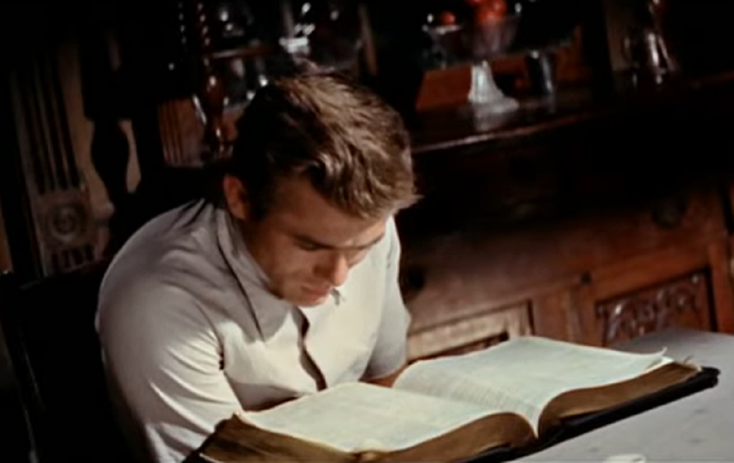 Screenshot: photo of James Dean in white shirt is reading a book - from the East Of Eden (1955).