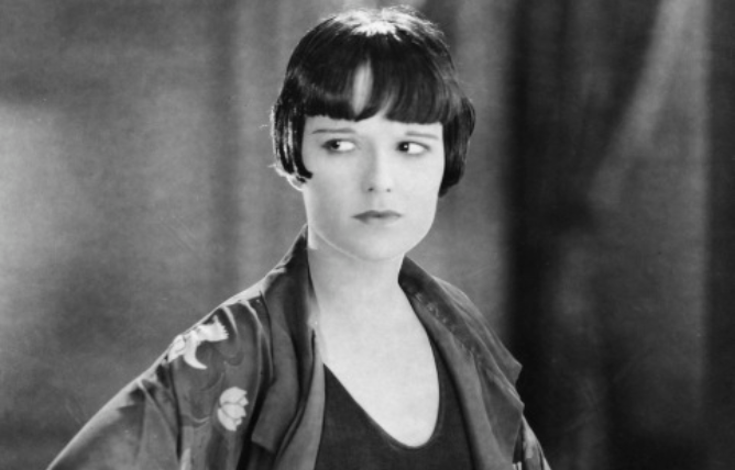 Grayscale Portrait Photo of the actress Louise Brooks, wearing a kimono an a black dress, looking to the left