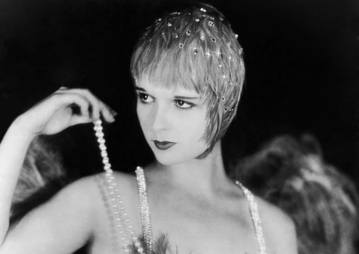 Grayscale Portrait Photo of the actress Louise Brooks, wearing glamorous outfit, pearl necklace