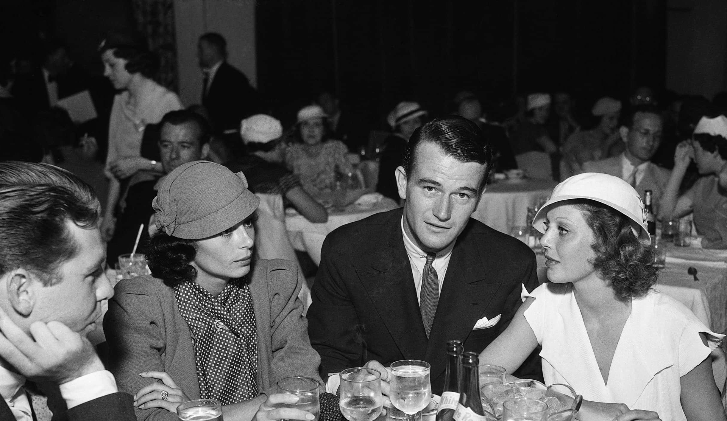 John Wayne dines with his bride, Josephine Saenz, At the right is Loretta Young, star actress