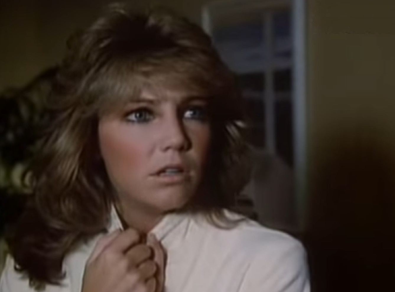 Screenshot of Heather Locklear wearing white jacket is looking at side scared - from City Killer (1984)