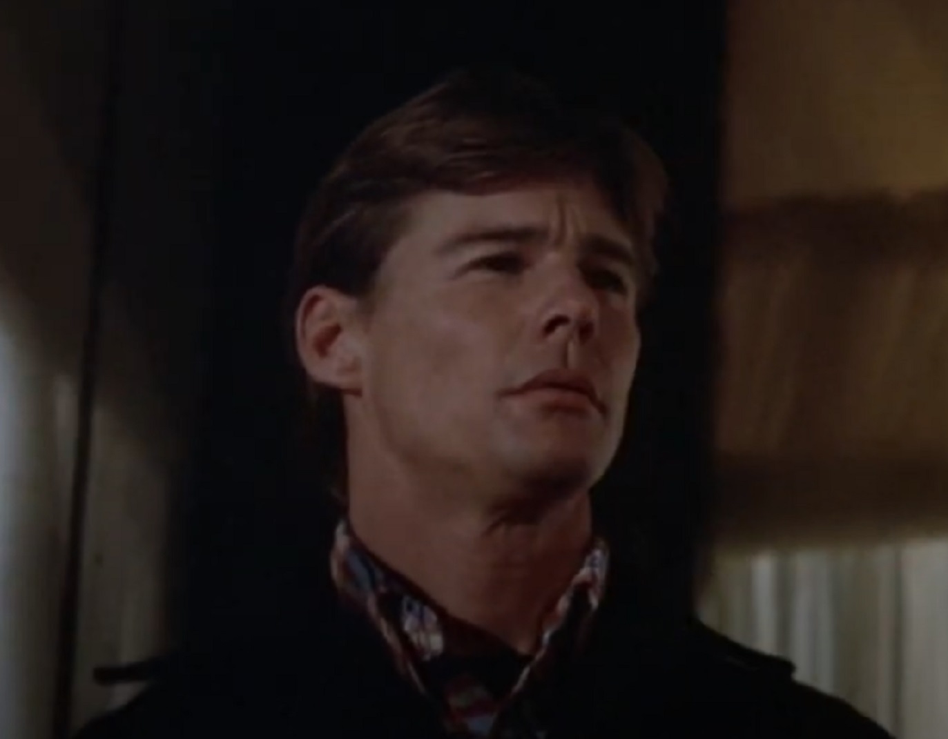 Screenshot: Jan-Michael Vincent wearing dark shirt is looking at front - from American International Pictures, Defiance (1980)
