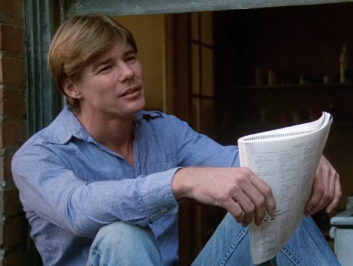 Screenshot: Jan-Michael Vincent wearing blue shirt is looking at side and smiling - from Damnation Alley (1977)
