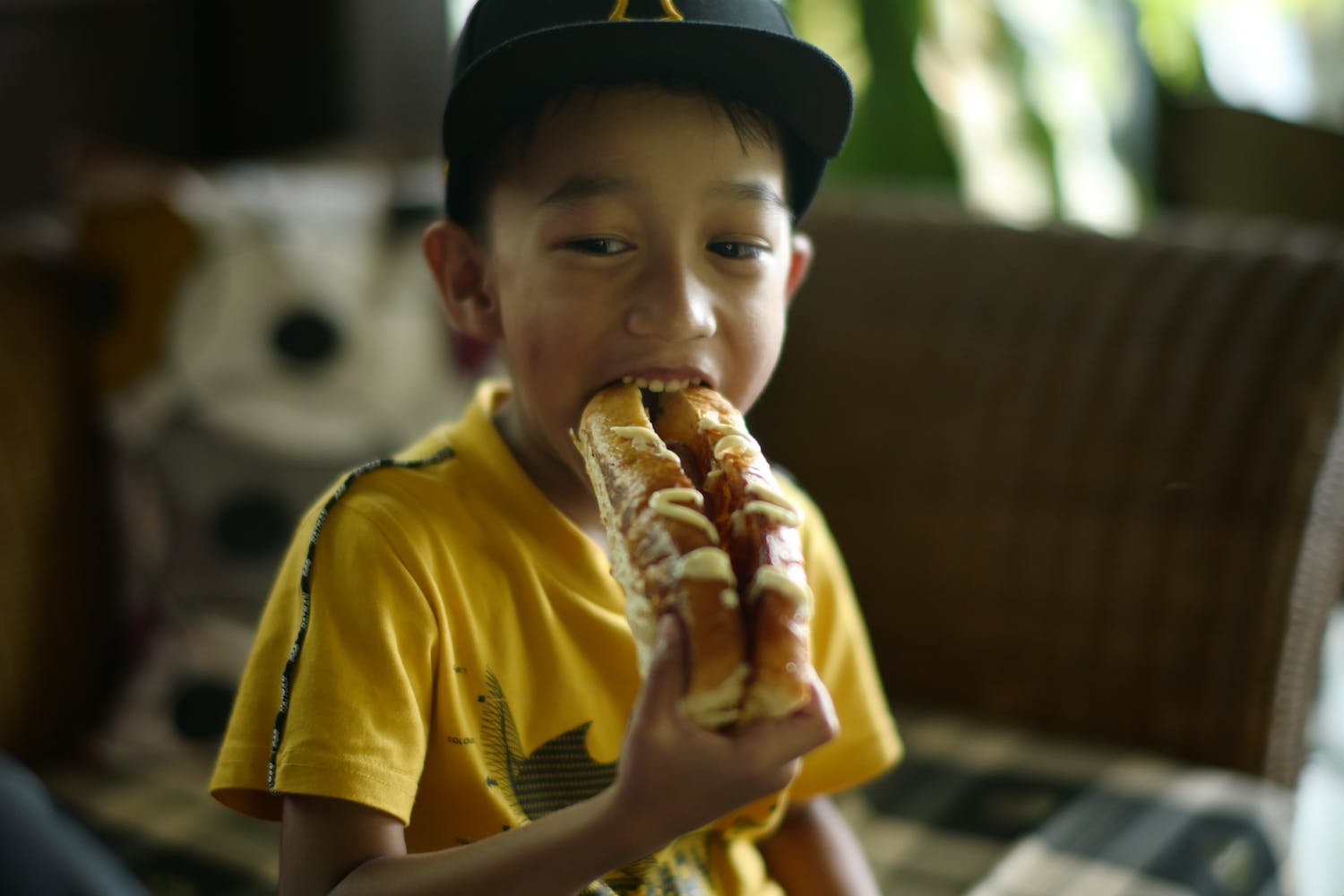 A Boy in Yellow Shirt Eating a Hotdog